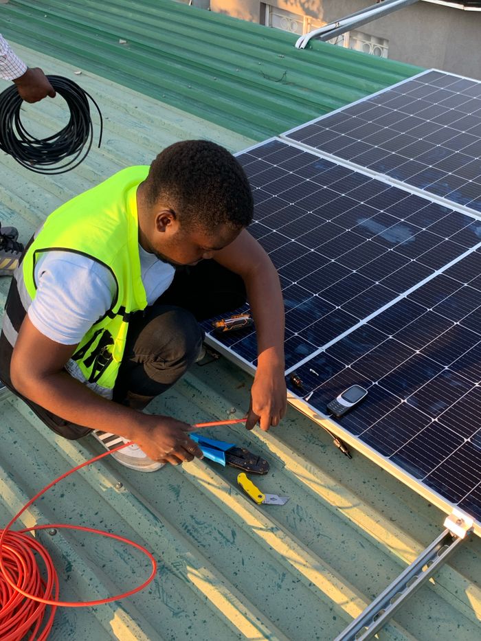 Home Technician working on solar panel installation with cables and tools on a sunny day.