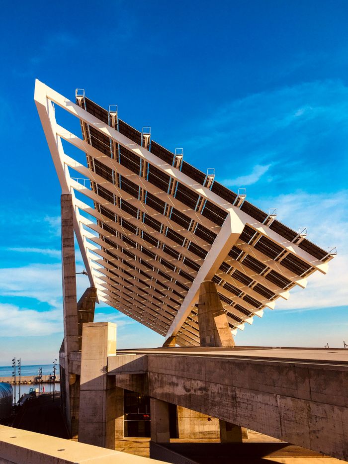 Services Photograph of a large solar panel installation set against a clear blue sky, highlighting renewable energy.