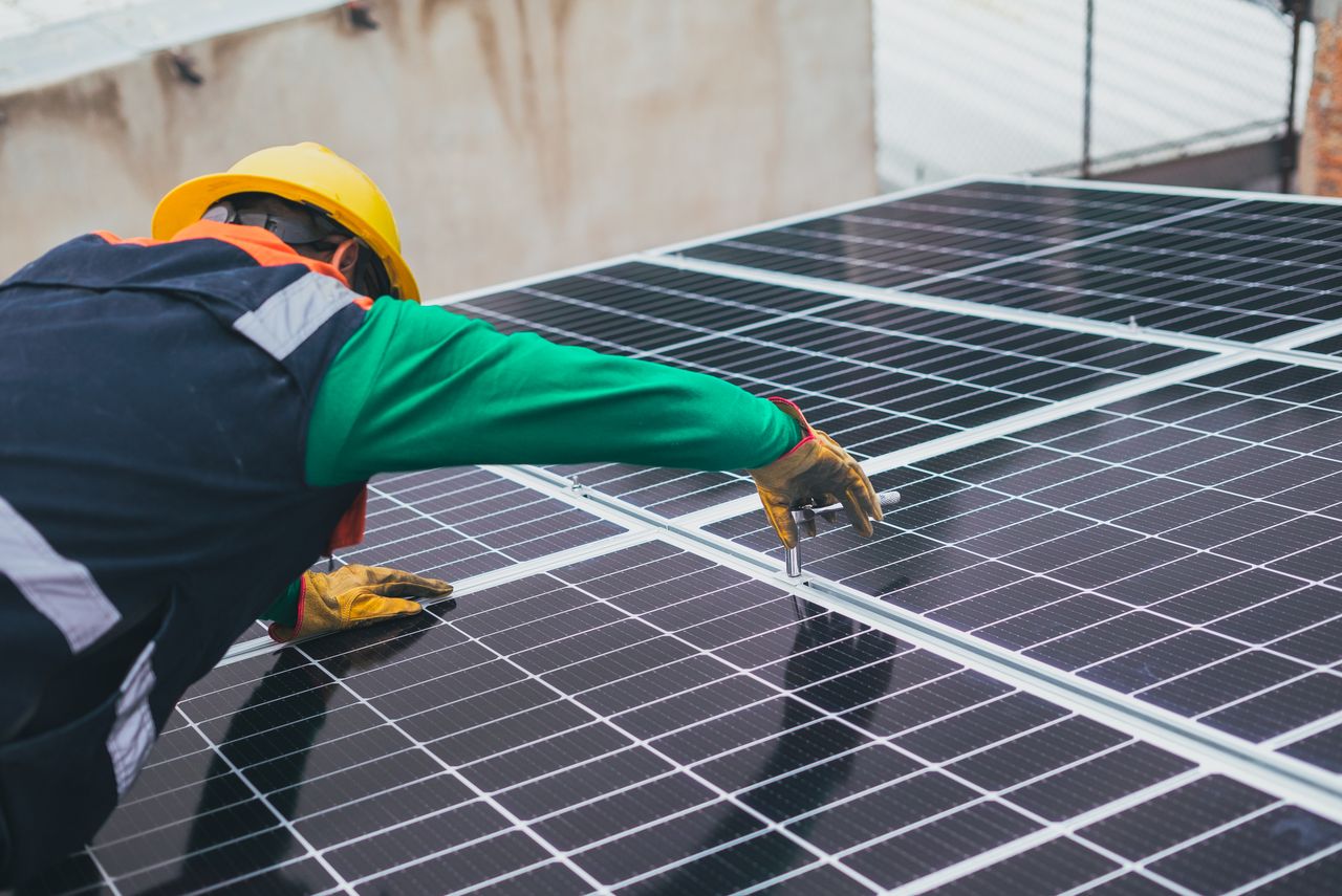Services Technician installing solar panels on a rooftop for sustainable energy solutions.