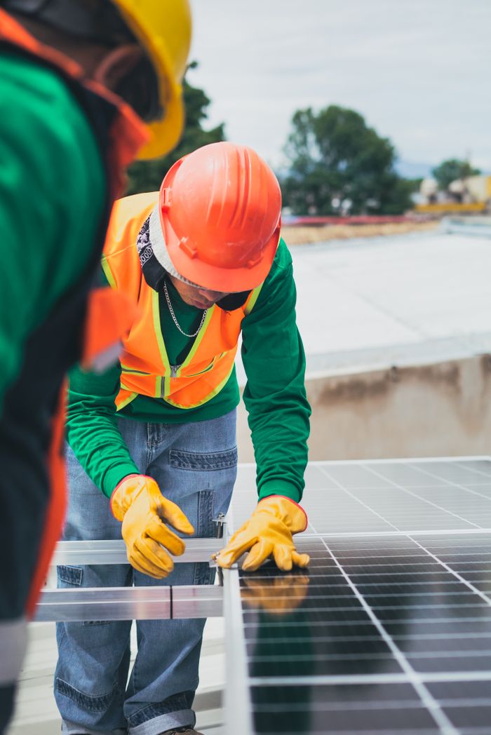 Services Worker in safety gear installing solar panels on a rooftop.