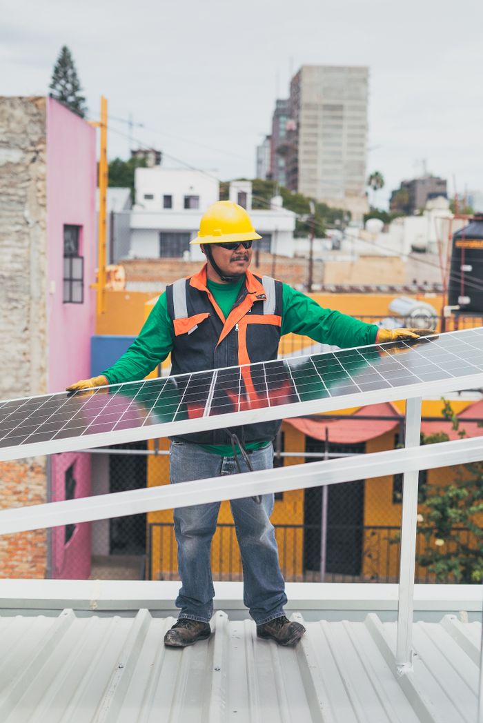 Services A solar technician adjusts photovoltaic panels on a colorful urban rooftop.